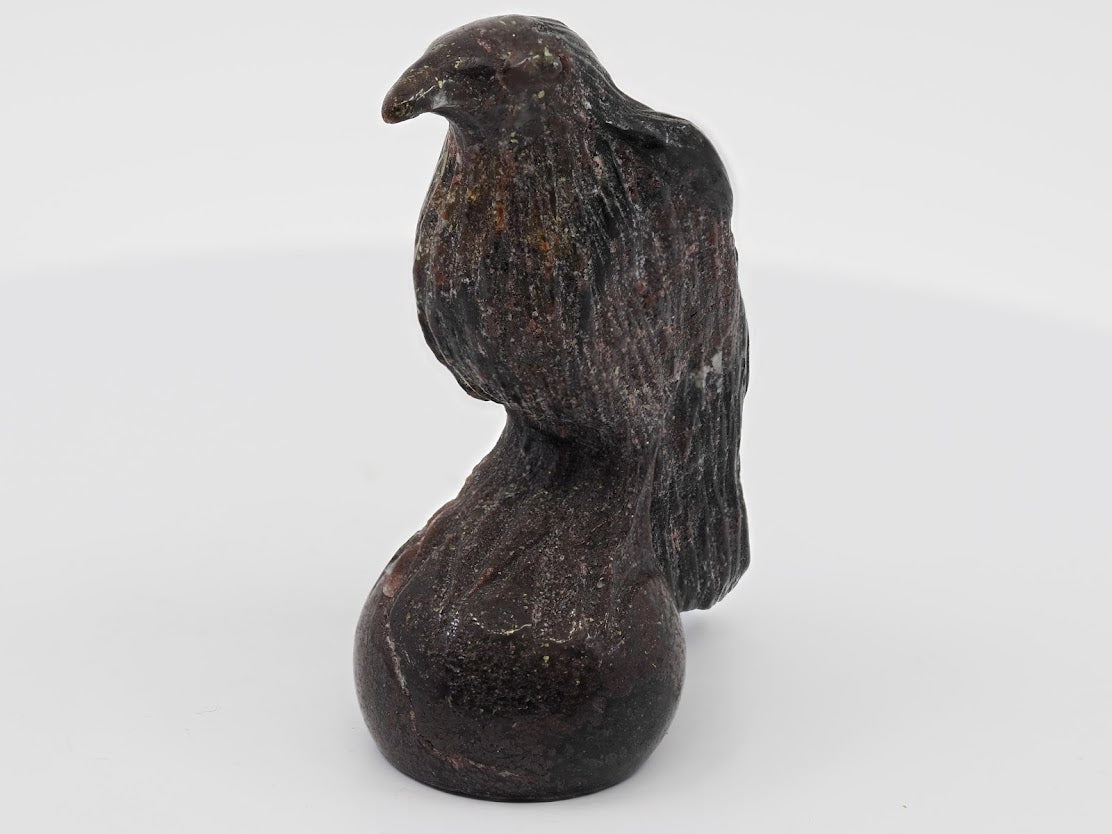 Front-facing view of a polished Garnet bird carving showing golden Pyrite flecks on the chest and beak.
