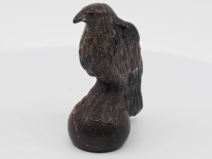 Front-facing view of a polished Garnet bird carving showing golden Pyrite flecks on the chest and beak.
