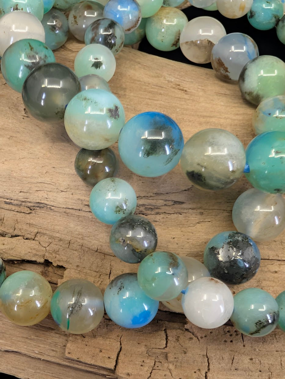 Macro shot of Gem Silica beads showcasing the rare "bottled ocean" effect with teal Chrysocolla suspended in translucent Quartz.