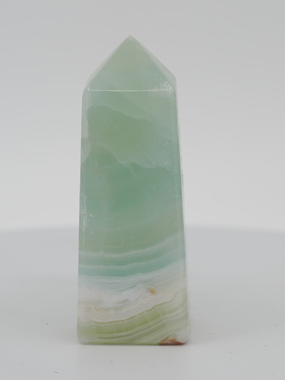 Polished Glass Pistachio Calcite tower featuring a translucent mint body and horizontal white aragonite basal banding.