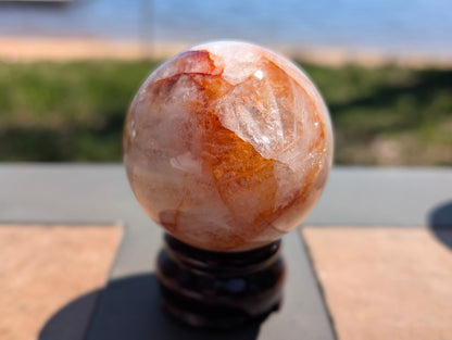 Exact-piece Golden Healer (ferruginous quartz) sphere from Brazil. 59mm variant GHS-04 featuring deep rust-red hematite ribbons cutting through milky quartz.