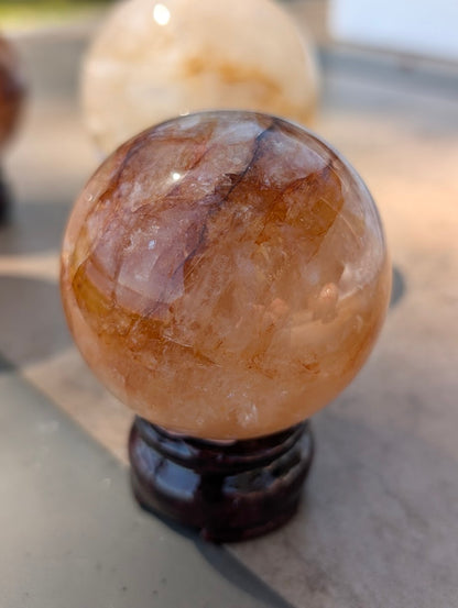 Exact-piece Golden Healer (ferruginous quartz) sphere from Brazil. 64mm variant GHS-06 heavily saturated with rich, fiery red and orange hematite.