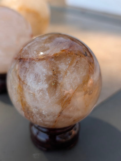 Exact-piece Golden Healer (ferruginous quartz) sphere from Brazil. 65mm variant GHS-03 offering a balanced mix of transparent windows and opaque iron-oxide banding.