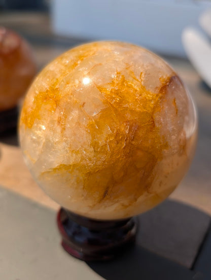 Close-up of Golden Healer quartz sphere GHS-02 highlighting unobstructed internal structure and brilliant reflective flashes.