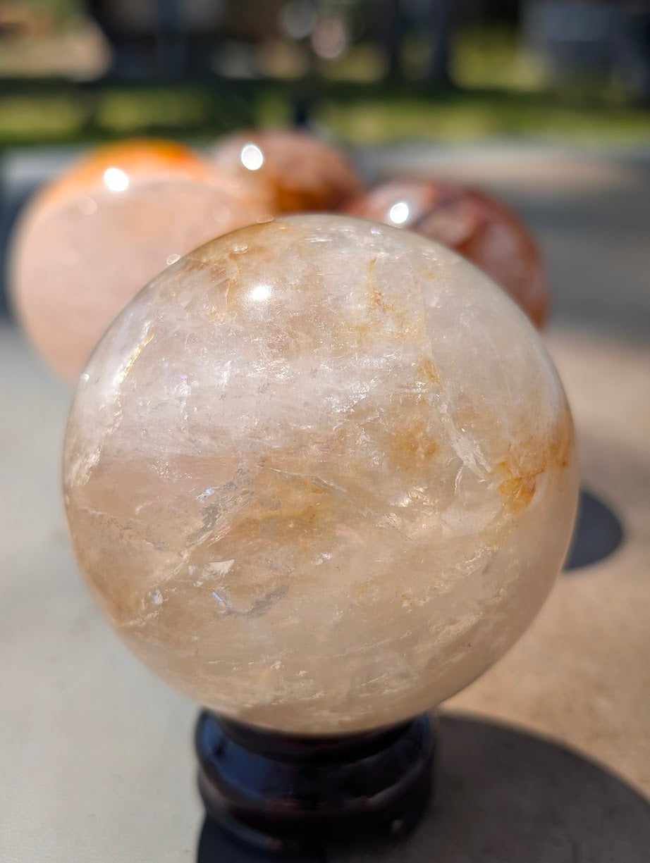 Exact-piece Golden Healer (ferruginous quartz) sphere from Brazil. 77mm variant GHS-02 boasting exceptional optical clarity and suspended golden veining.