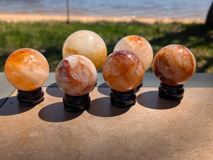 Group of six premium Golden Healer ferruginous quartz spheres from Brazil displaying vibrant iron-oxide inclusions.