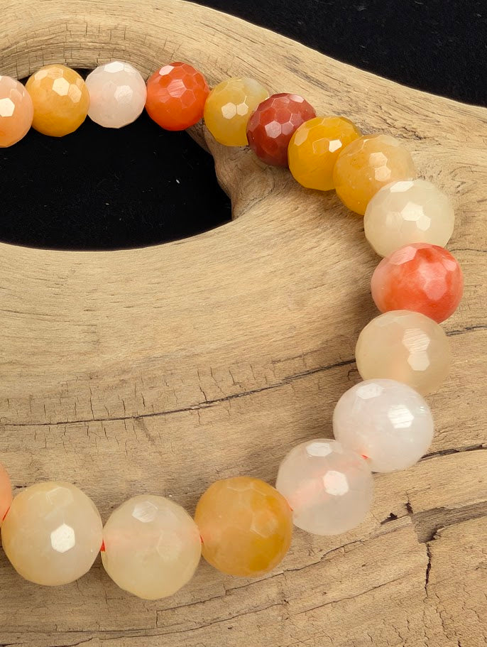 Macro close-up of 8mm faceted Golden Jade beads highlighting geometric surface cuts and a coloured stretch cord.