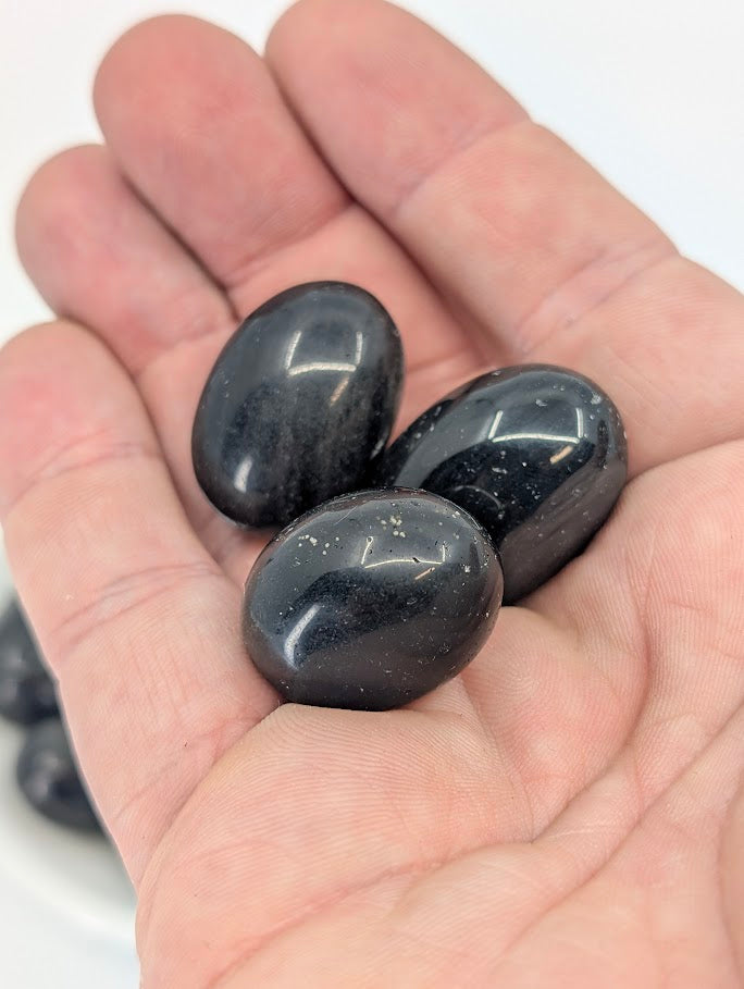 Golden Obsidian tumbled stones shown in hand for scale