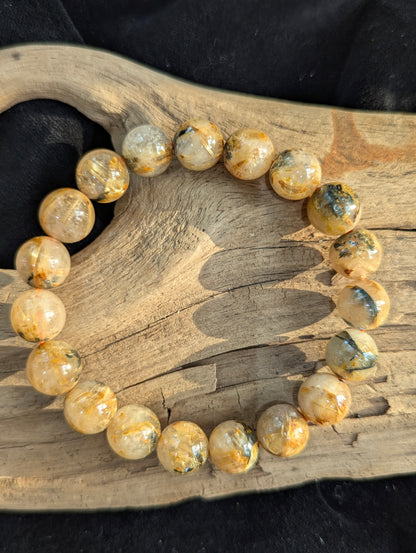 An 11mm AA-grade Golden Rutilated Quartz bracelet. The large polished beads highlight the striking visual contrast between clear quartz and bright golden rutile.