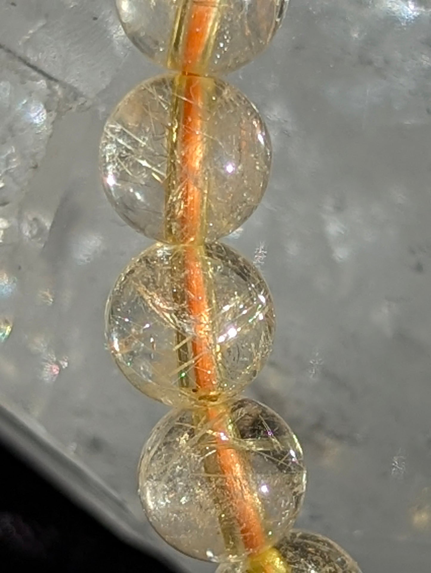 Macro close-up view of polished 6mm Golden Rutilated Quartz spheres, highlighting the high clarity of the host quartz and the intricate, metallic golden rutile needle network.