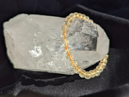Premium 6mm Golden Rutilated Quartz beaded stretch bracelet worn on the wrist to demonstrate its 17cm circumference scale and continuous mineral profile under balanced lighting.