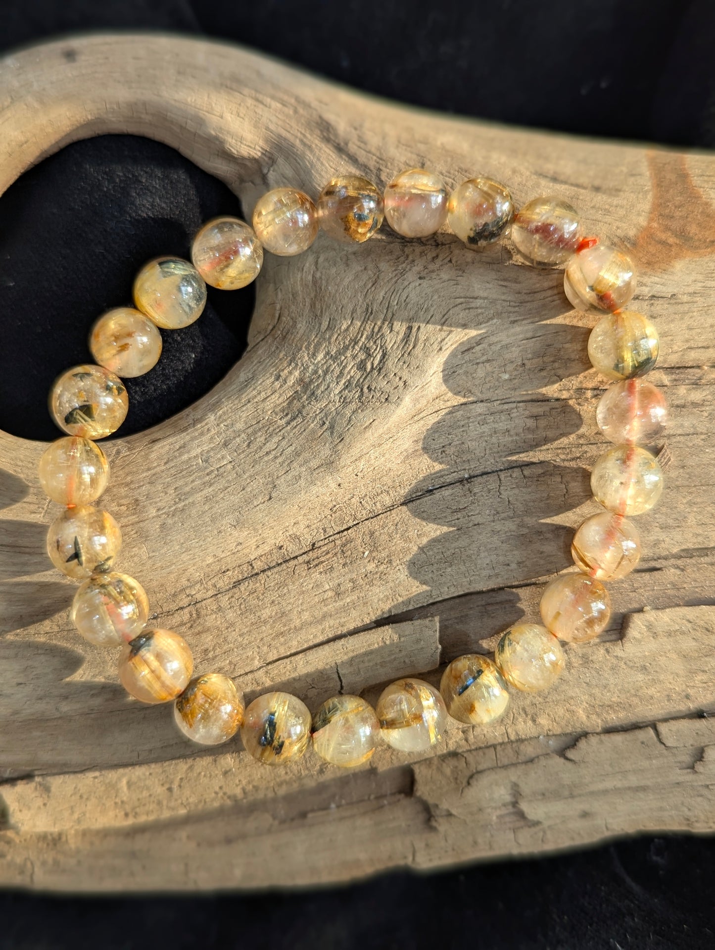 An 8mm Golden Rutilated Quartz bracelet from Brazil. Transparent quartz beads polished to a high shine, featuring natural yellow rutile needle inclusions.