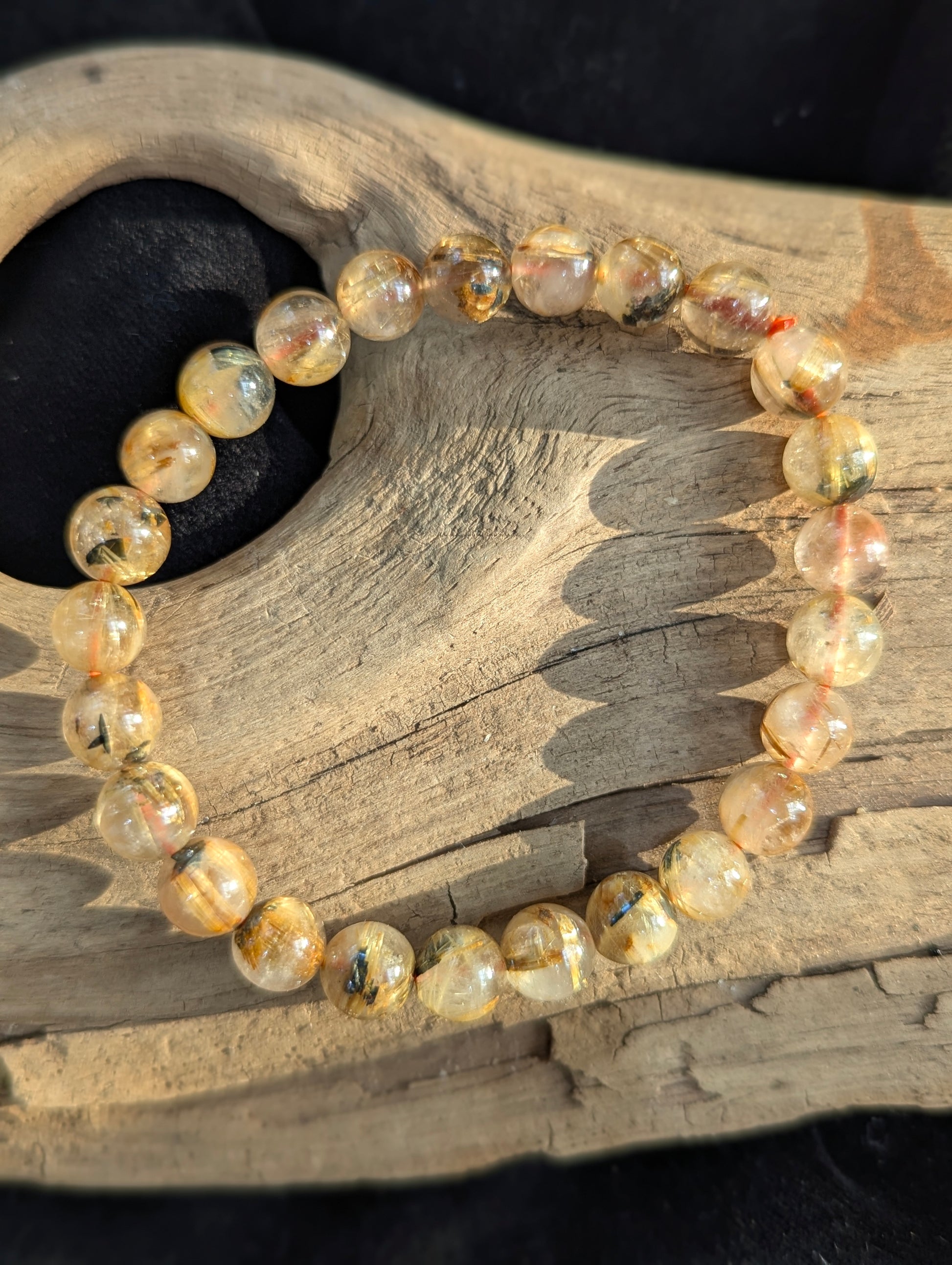 An 8mm Golden Rutilated Quartz bracelet from Brazil. Transparent quartz beads polished to a high shine, featuring natural yellow rutile needle inclusions.