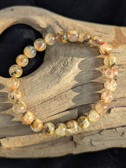 An 8mm Golden Rutilated Quartz bracelet from Brazil. Transparent quartz beads polished to a high shine, featuring natural yellow rutile needle inclusions.