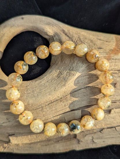 A 9mm Golden Rutilated Quartz stretch bracelet. The macrocrystalline quartz matrix provides clear visibility of the dense titanium dioxide needles within.
