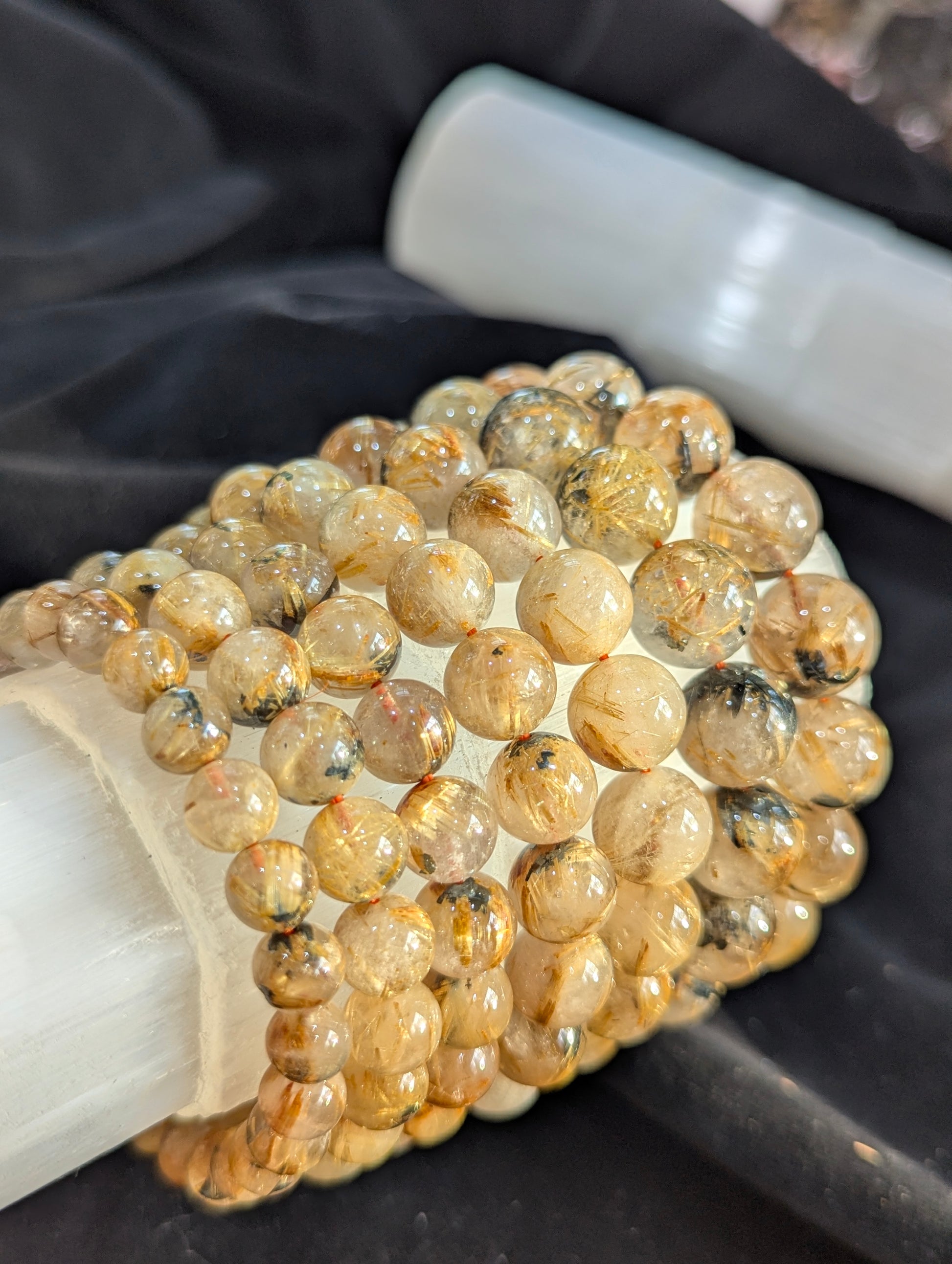 Close-up view of Golden Rutilated Quartz beads, capturing how light refracts brilliantly off the dense, metallic internal rutile structures.