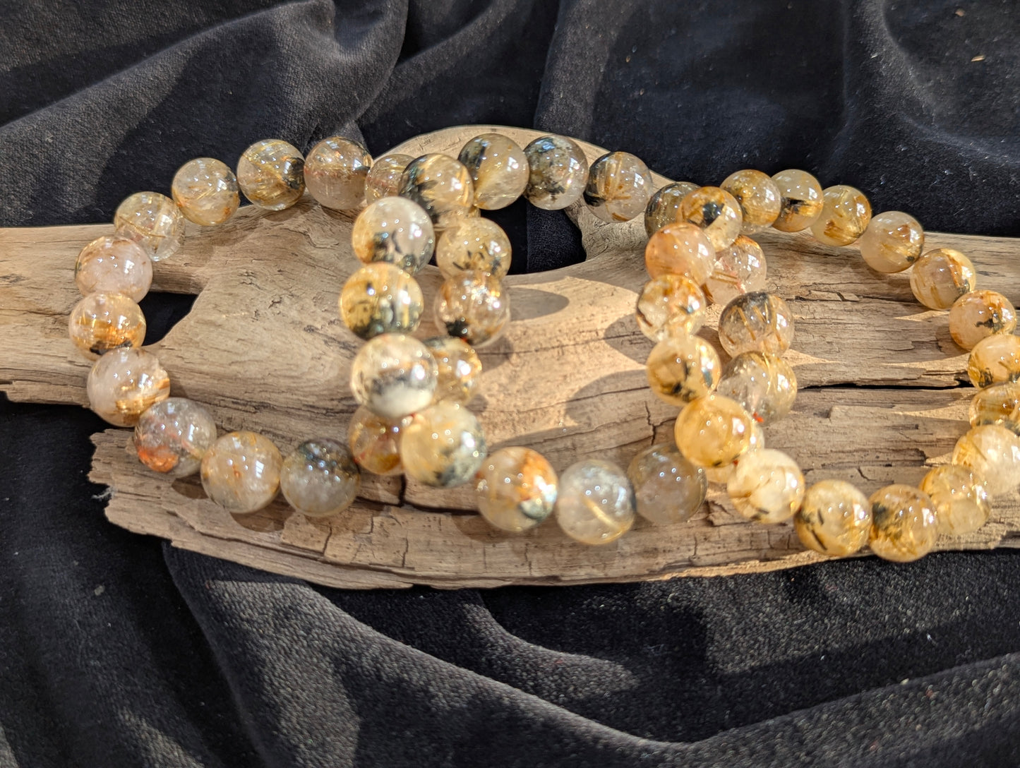 A collection of premium Golden Rutilated Quartz stretch bracelets from Brazil, ranging from 8mm to 13mm, showing high-clarity quartz and dense golden inclusions.