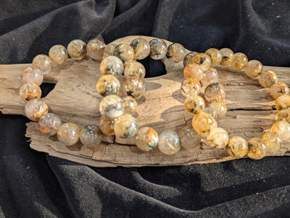A collection of premium Golden Rutilated Quartz stretch bracelets from Brazil, ranging from 8mm to 13mm, showing high-clarity quartz and dense golden inclusions.