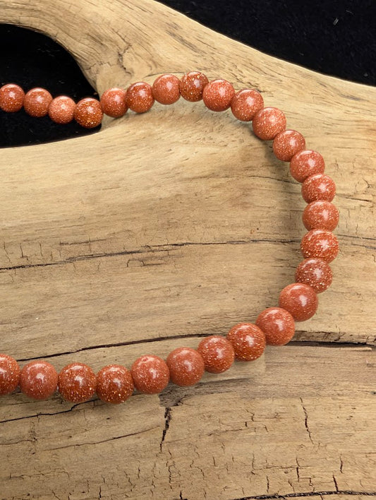 Macro close-up of 4mm polished Golden Sandstone beads highlighting the high-gloss finish and the metallic copper flecks.