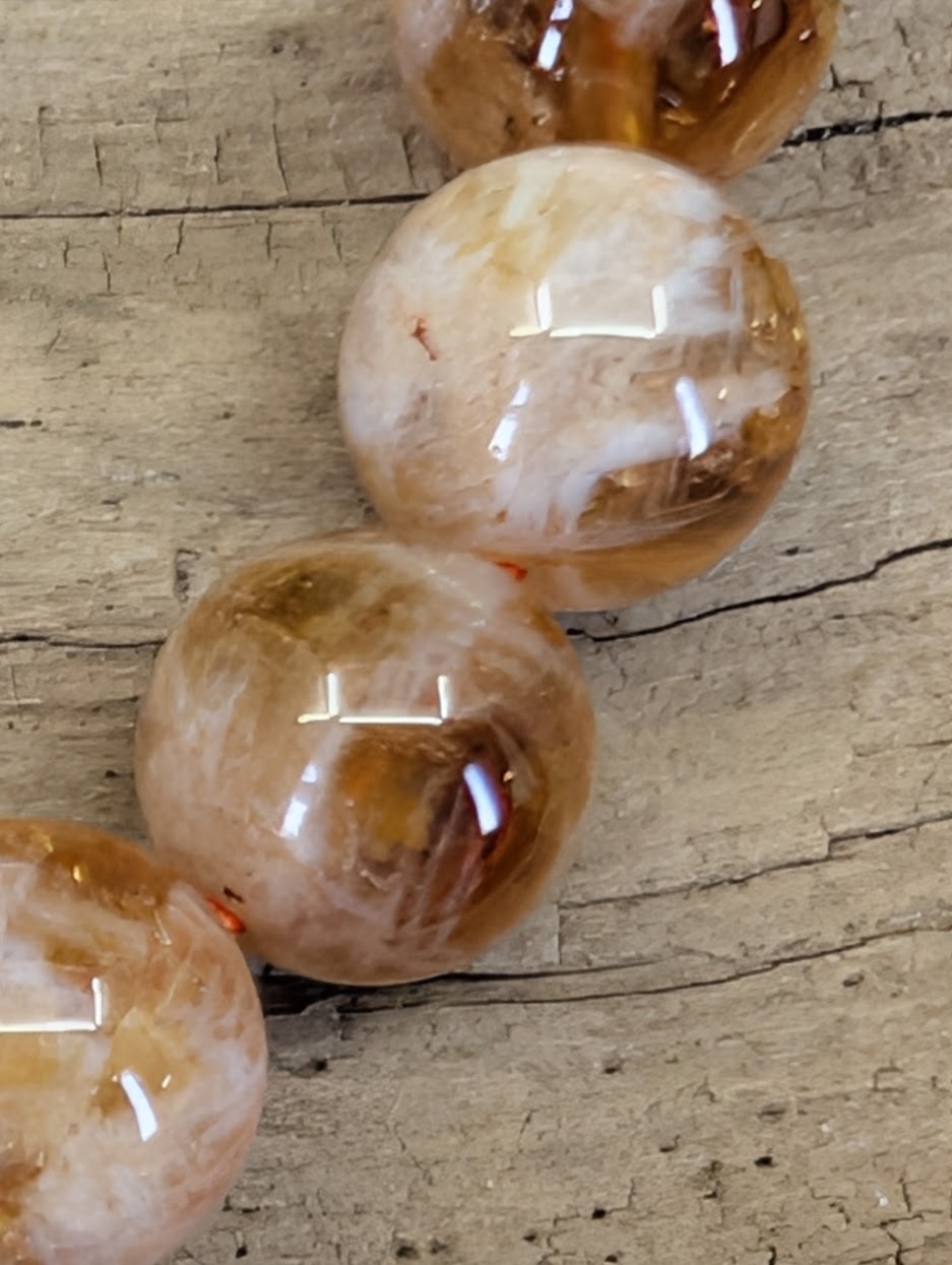 Extreme close-up of natural inclusion quartz beads highlighting the fiery orange sericite phantoms and high-clarity crystal.