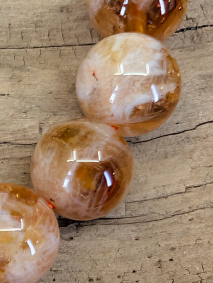 Extreme close-up of natural inclusion quartz beads highlighting the fiery orange sericite phantoms and high-clarity crystal.
