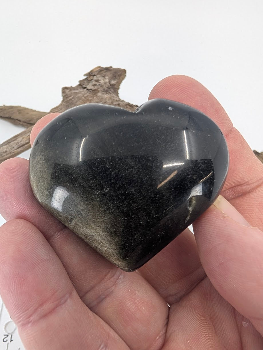 Hand holding a Golden Sheen Obsidian heart showing bronze shimmer.