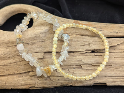 Two golden rutile bracelets on a piece of driftwood with a dark background