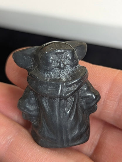 Angled front view of a hand-held matte Black Obsidian Gorku carving.