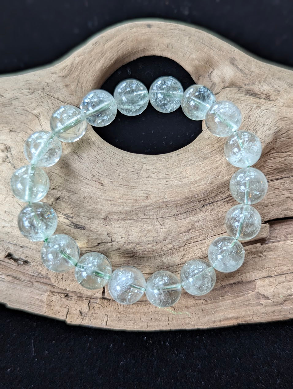 10mm Green Amethyst (Prasiolite) Bracelet, showing pale mint colour and delicate internal inclusions on driftwood.