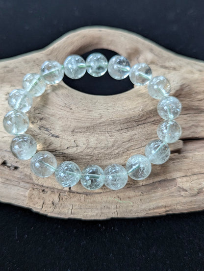 11mm Green Amethyst (Prasiolite) Bracelet, showing pale mint colour and delicate internal inclusions on driftwood.