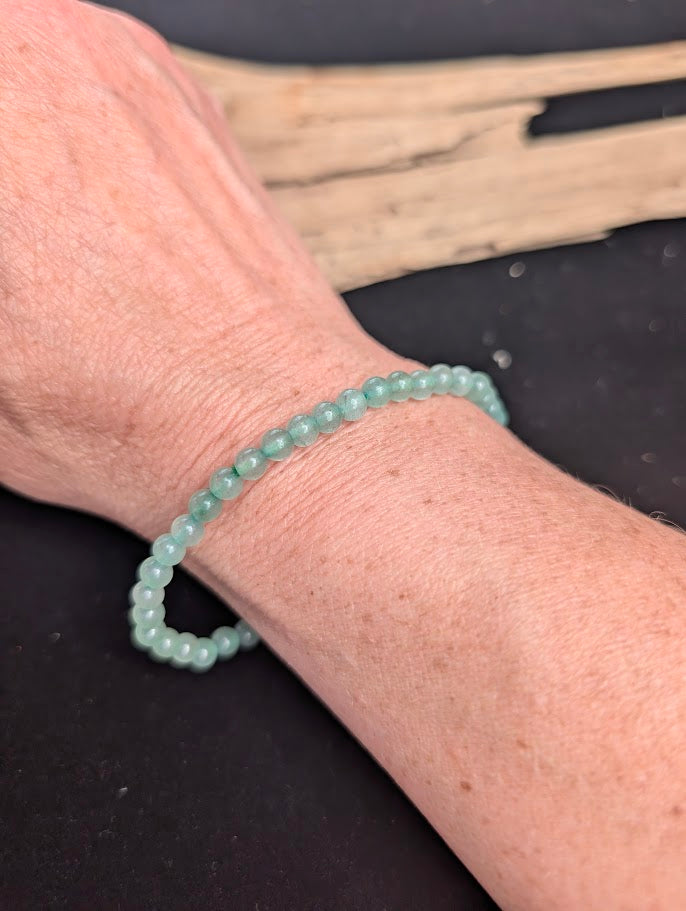 Natural sunlight on a 4mm soft green Green Aventurine stretch bracelet worn on a wrist.