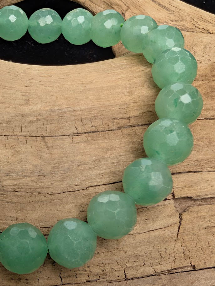 Macro close-up of 8mm faceted Green Aventurine beads highlighting the geometric cut and subtle natural aventurescence.
