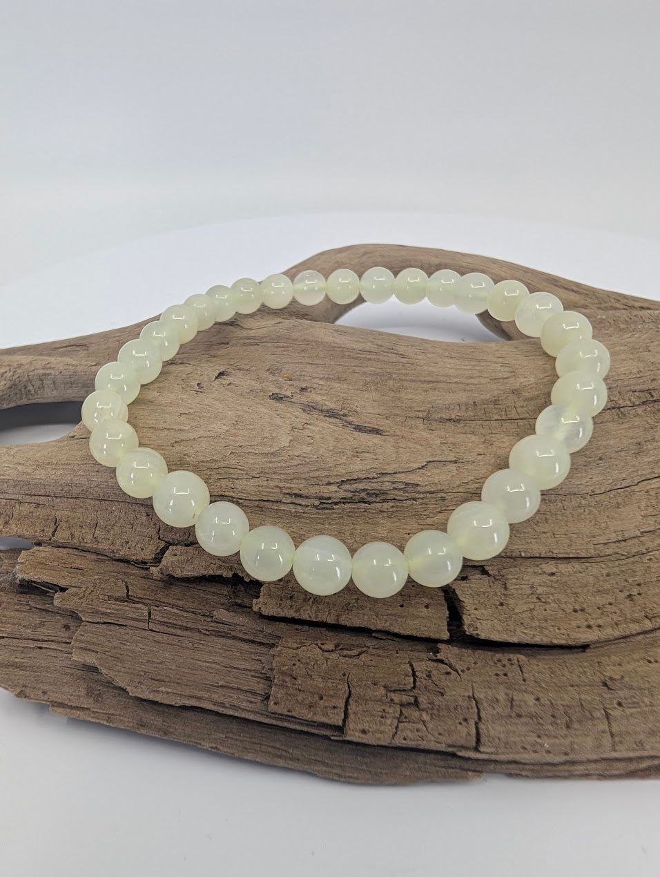 6mm Green Calcite bracelet displayed on driftwood