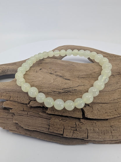 6mm Green Calcite bracelet displayed on driftwood