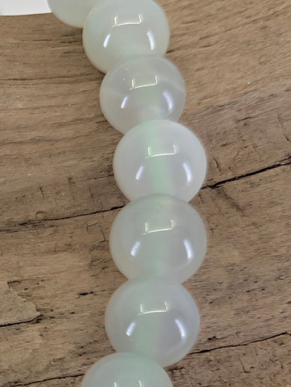 Macro view of 6mm Garnierite beads showing high-gloss polish and authentic moonstone light play.