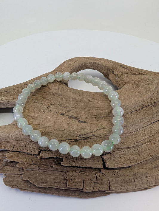 6mm Green Moonstone bead bracelet from Madagascar showing pale mint-green color on natural wood.