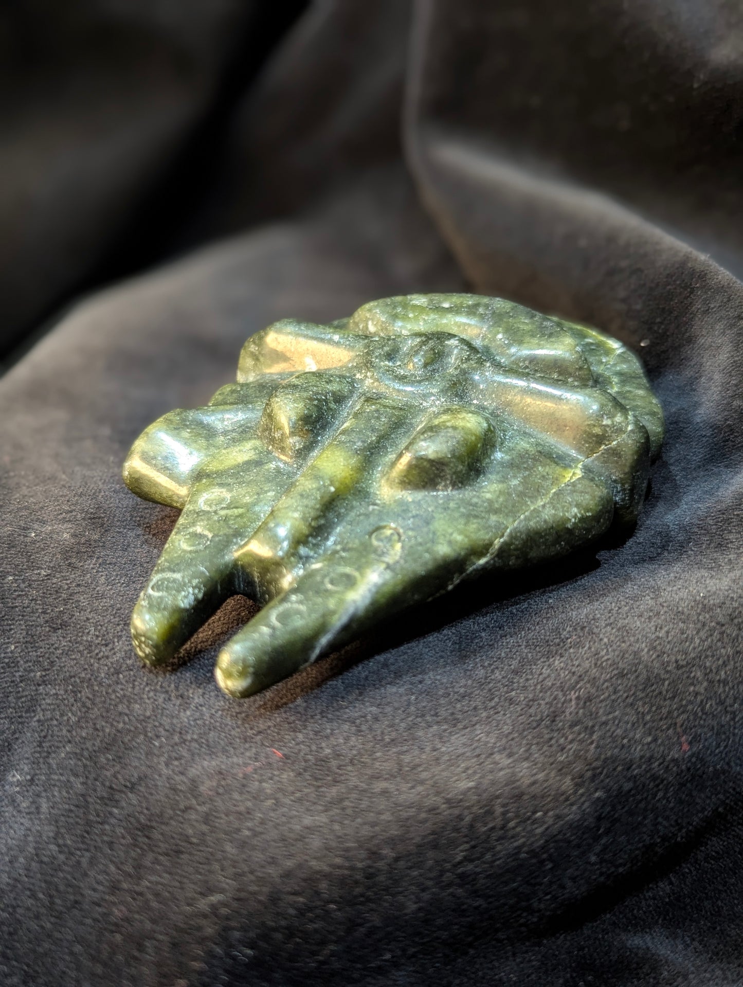 Angled side view of carved green Nephrite Jade Millennium Falcon showing front mandibles and cockpit