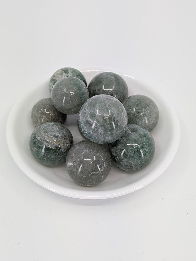Green Strawberry Quartz mini spheres in a white bowl showing translucent green tones