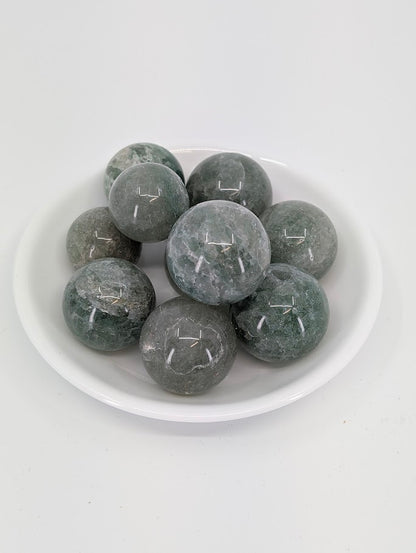 Green Strawberry Quartz mini spheres in a white bowl showing translucent green tones