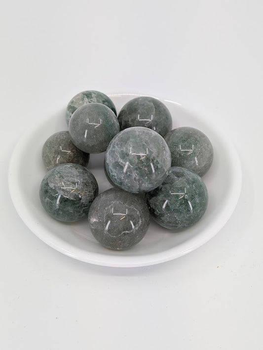Green Strawberry Quartz mini spheres in a white bowl showing translucent green tones