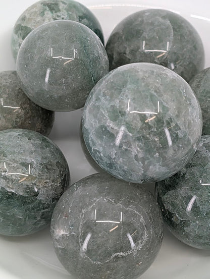Close-up of polished Green Strawberry Quartz spheres with shimmering inclusions