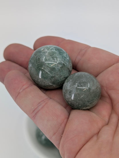 Green Strawberry Quartz spheres held in hand for size reference