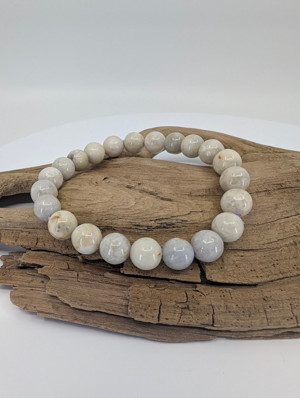8mm hackmanite bracelet on driftwood showing neutral grey and white beads
