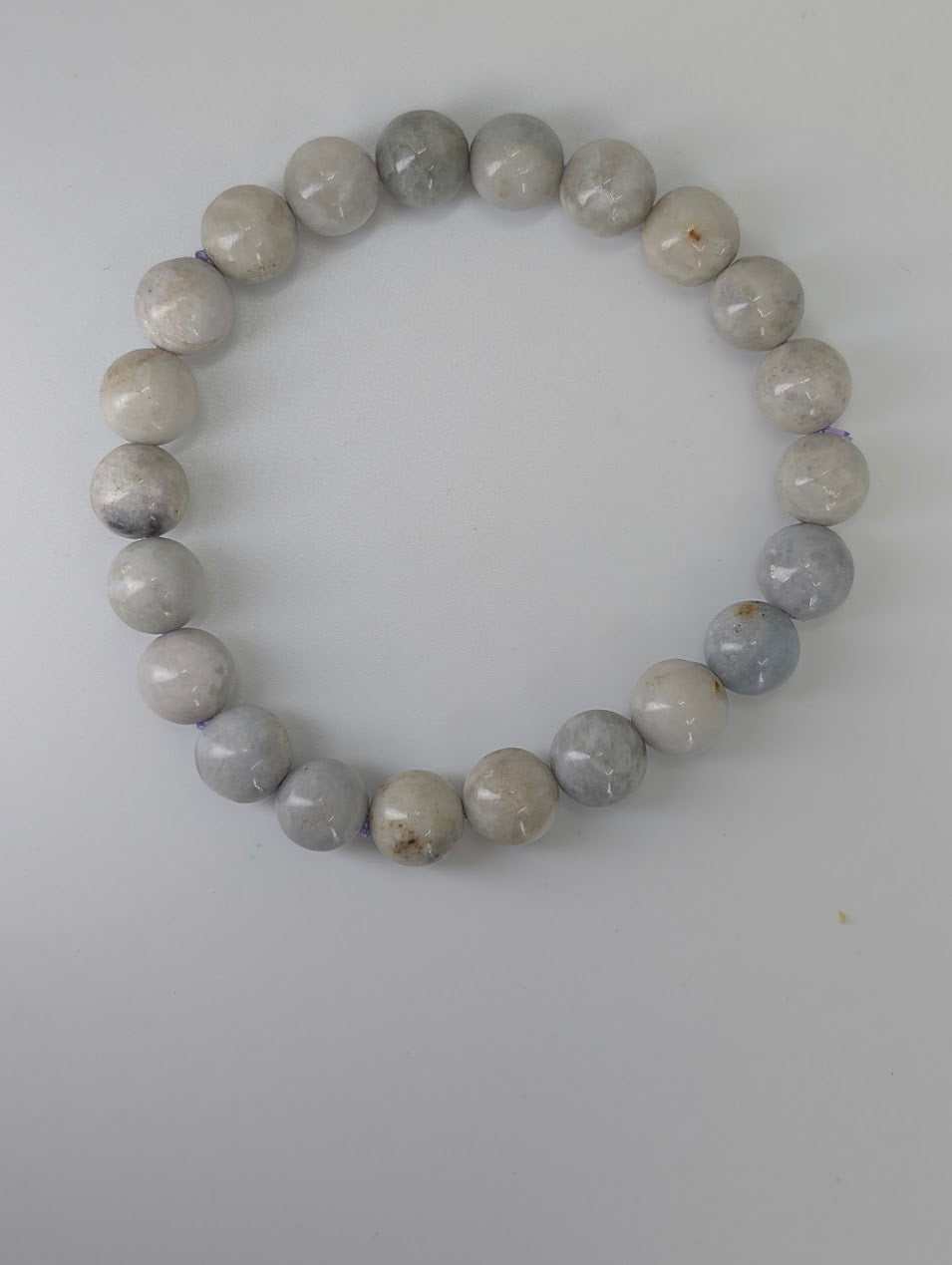 Overhead view of 8mm hackmanite bracelet in a circle on white background