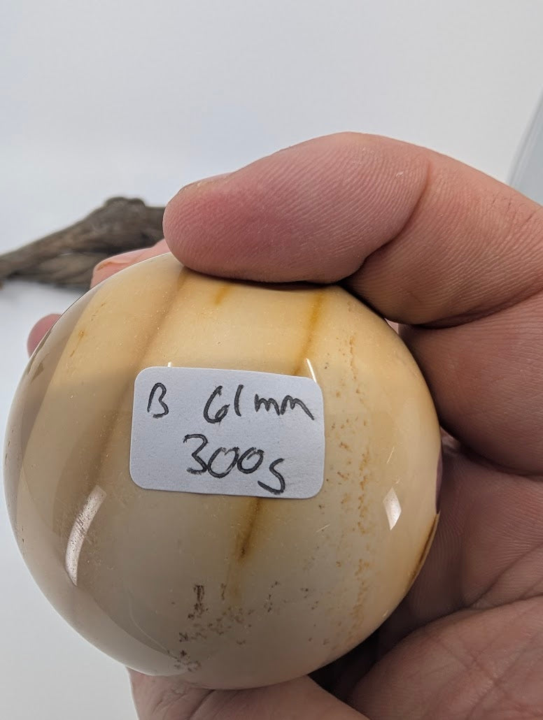 Hand holding a 61mm Mookaite sphere (300g) showing scale.
