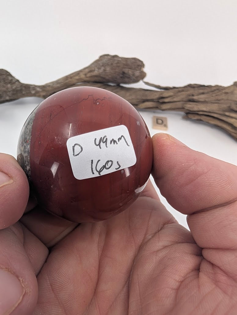 Hand holding a 49mm Mookaite sphere (160g).