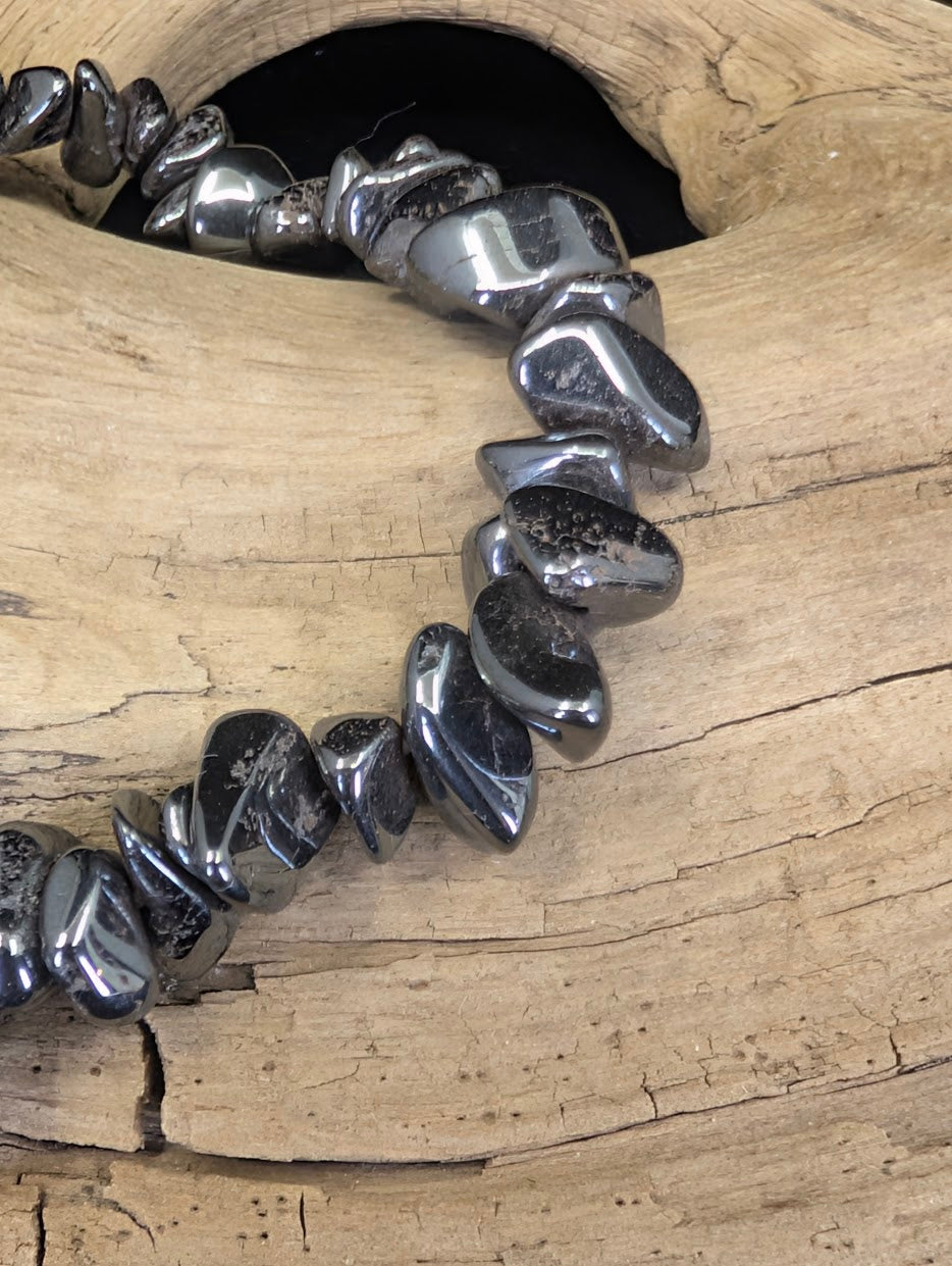 Close-up of polished Hematite chips, showcasing the reflective, sub-metallic finish and smooth, organic shapes of the mineral shards.