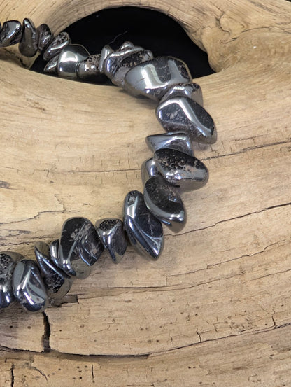 Close-up of polished Hematite chips, showcasing the reflective, sub-metallic finish and smooth, organic shapes of the mineral shards.