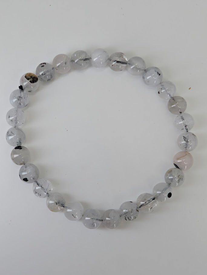 Top-down image of 6mm and 7mm Herkimer style quartz bracelets on driftwood