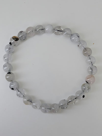 Top-down image of 6mm and 7mm Herkimer style quartz bracelets on driftwood